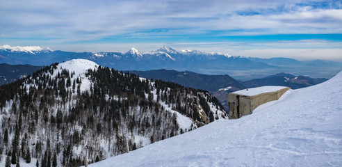 Pillbox (a part of Rupnik defense line) on the Top of the Ratitovec mountain overlooking the Kosmati vrh and Kamnik-Savinja Alps on a winter day