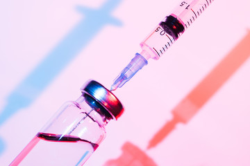 Glass bottle with vaccine and syringe for injection. Concept photo about the threat of viral diseases or drug addiction.