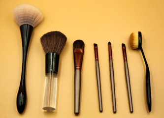 makeup brushes, many makeup brushes on an isolated yellow background