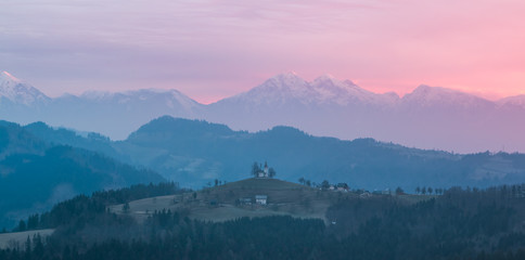 View of the alps in the morning with the st. Tomaz church on the top of the hill, Slovenia