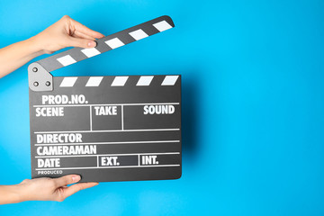 Fototapeta premium Woman holding clapperboard on color background, closeup with space for text. Cinema production