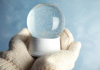 Woman holding empty snow globe on color background, closeup