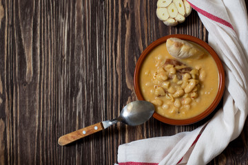 White bean stew, pasulj, bread, traditional Balkan cuisine, wooden background, top view