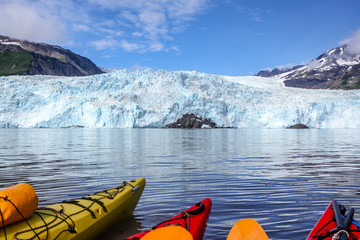Tips of kayaks in water in front of Aialik Glacier, Aialik Bay, Alaska, USA. Tips of kayaks in foreground, glacier in background.