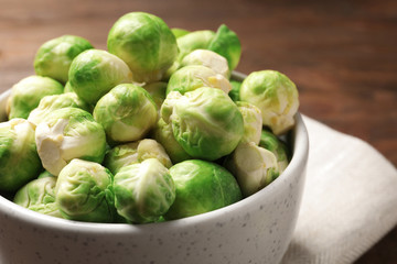 Bowl of fresh Brussels sprouts on table, closeup. Space for text