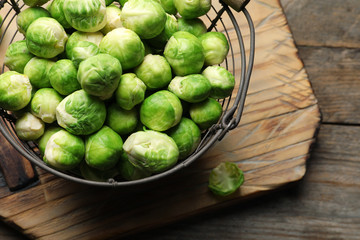 Metal basket with fresh Brussels sprouts on wooden background, top view