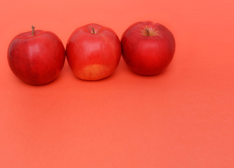 three red apples on the red background