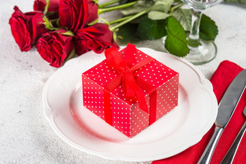 Holiday table setting with plate, roses and present.