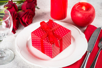 Holiday table setting with plate, roses and present.