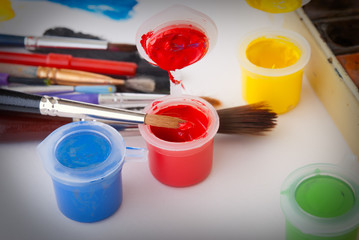 Different colored paints and brushes on a white background