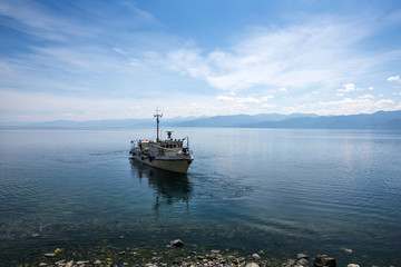 The ship departs from the shore. Sunny summer day. Rocky shore.