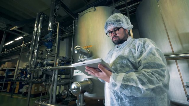 Male winery worker is standing near a canister with lye