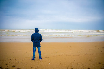 Young man in jacket on sandy beach of Rimini in winter, Italy