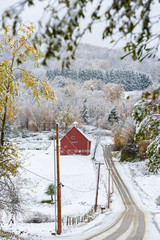 Snow covered road leading to a red barn in Stowe, Vermont, USA