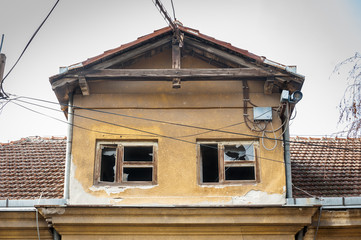 Fototapeta na wymiar Damaged house, Small old and abandoned damaged house cracked windows with broken glass demolished by the earthquake destruction closeup
