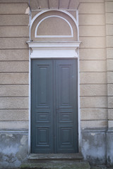 Drzwi drewniane szare do beżowego budynku - obrazy, fototapety, plakaty