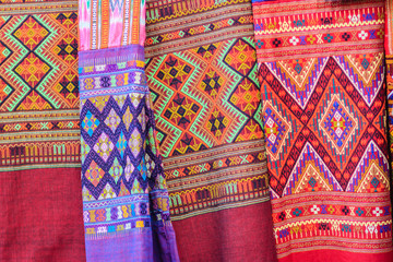 Fototapeta premium Colorful of native thai style silk and textiles pattern. Beautiful handmade woven fabrics thai silk fabric textured, with different native style patterns.