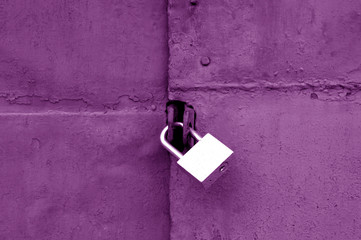 Old padlock on metal gate in purple color.