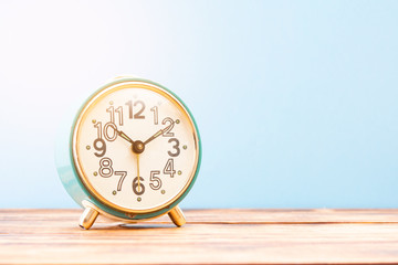 Turquoise retro alarm clock on a wooden table with sun rays
