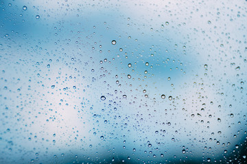 Abstract raindrop on car glass window and blurred blue sky on background while raining season