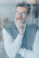 pensive retired man thinking at home near window