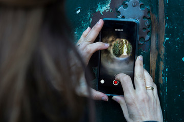 Rome, February 07, 2018: A tourist takes a pictures of St. Peter's dome through the keyhole on the gate to the headquarters of the Knights of Malta on Rome's Aventine Hill. Peek through this keyhole o
