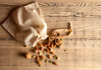 Almond nuts, hazelnuts, walnuts and sweet seeds in a burlap bag on a wooden background. Top view.