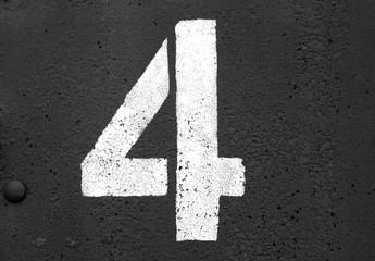 Number 4 in stencil on metal wall in black and white.