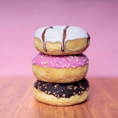 Stack of  sweet glazed doughnuts on pink background. 