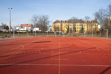Boisko tartanowe w mieście z budynkiem i parkingiem w tle © Seance_Photo_Sylwia