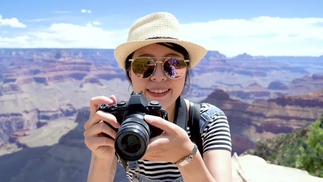 cheerful backpacker photographer taking picture of beautiful nature desert view in Grand Canyon National Park. young girl in sunglasses holding camera photographing in wild hiking trip on sunny day.