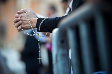 Rome Italy, June 18, 2017 : A Woman prays the rosary before the beginning of the celebration of the Holy Mass prior to the Corpus Domini procession from St. John at the Lateran Basilica to St. Mary Ma - obrazy, fototapety, plakaty