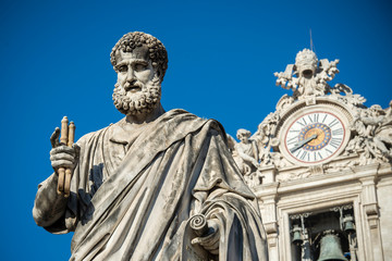 Fototapeta na wymiar Vatican City, March 29, 2017: Statue of Saint Peter and Saint Peter's Basilica clock at background.