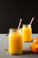 Fototapeta na wymiar Fresh orange juice in glass jars, side view. Close-up.