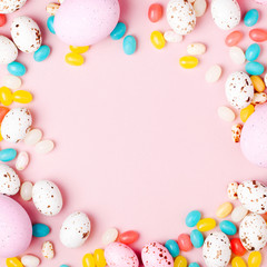 Stylish frame made of Easter candy chocolate eggs and Jellybean on pink background