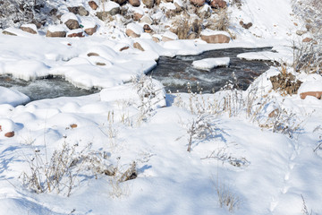 smooth movement of wild water in a river in winter with snow and ice on rocks and stones in beautiful nature