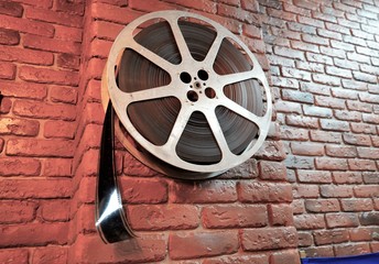 Of vintage film reel and strips hangs on a brick wall. 35 mm film reel