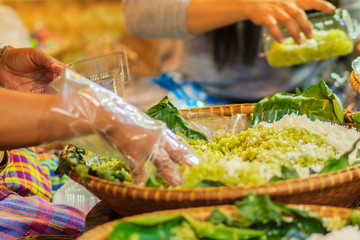 Thai vendor is selling shredded rice grain dessert to the customer at night market. Steamed shredded rice grain with coconut, This Thai desert is called 