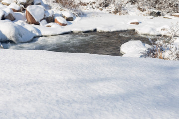 smooth movement of wild water in a river in winter with snow and ice on rocks and stones in beautiful nature