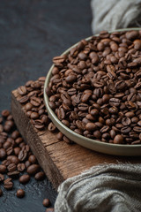 Fototapeta premium Coffee beans in a plate on a wooden stand. Close-up photography with low key.