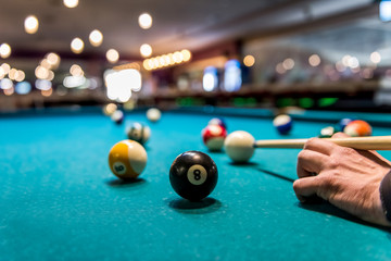 Hand as rack for cue on billiard table with balls