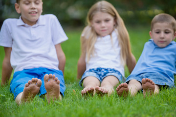 Happy children show their feet close up in the park. Barefoot on the green grass