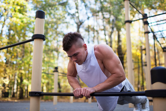 fitness, sport, training and lifestyle concept - young adult fit man doing push-ups outdoors