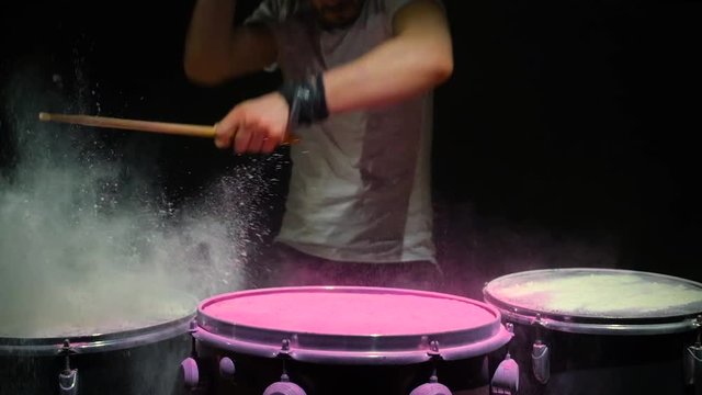 Red holi powder bounces off drum in shockwave pattern, slow motion. black background.