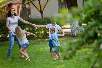 Naklejka na ściany i meble Mother and children dance on the lawn in the park