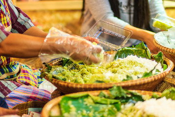 Thai vendor is selling shredded rice grain dessert to the customer at night market. Steamed shredded rice grain with coconut, This Thai desert is called 