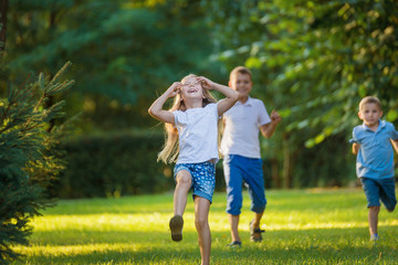 Naklejka na ściany i meble Boys and girl play and run a race on the lawn outdoor