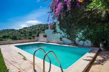 swimming pool in the backyard of a mediterranean style house on a sunny day