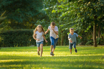 Naklejka na ściany i meble Boys and girl play and run a race on the lawn outdoor