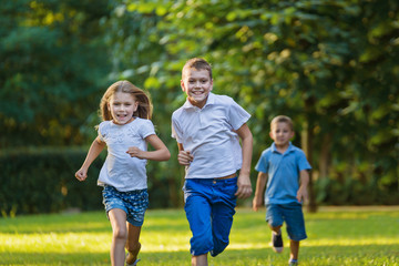 Boys and girl play and run a race on the lawn outdoor